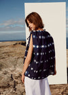 A sleeveless, v-neck, hand-dyed indigo shibori cotton top with adjustable drawstring ties on the shoulders and neckline