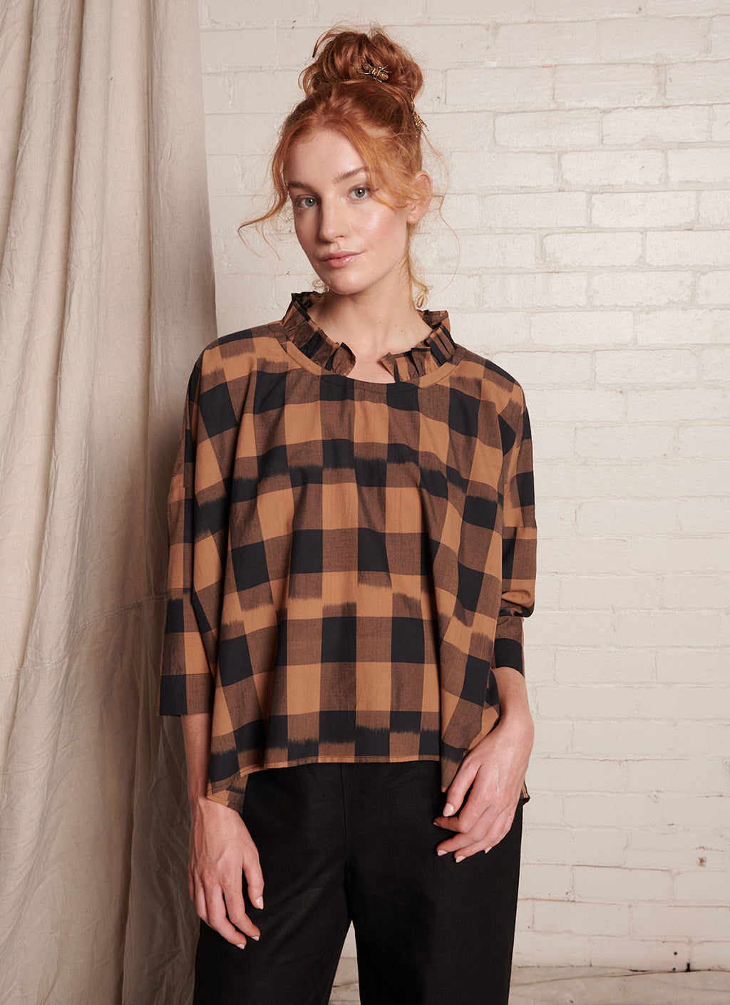 A bronze plaid, relaxed fit, square-cut top with 3/4 sleeves, frilled collar and tie closure at the back made from handwoven ikat cotton
