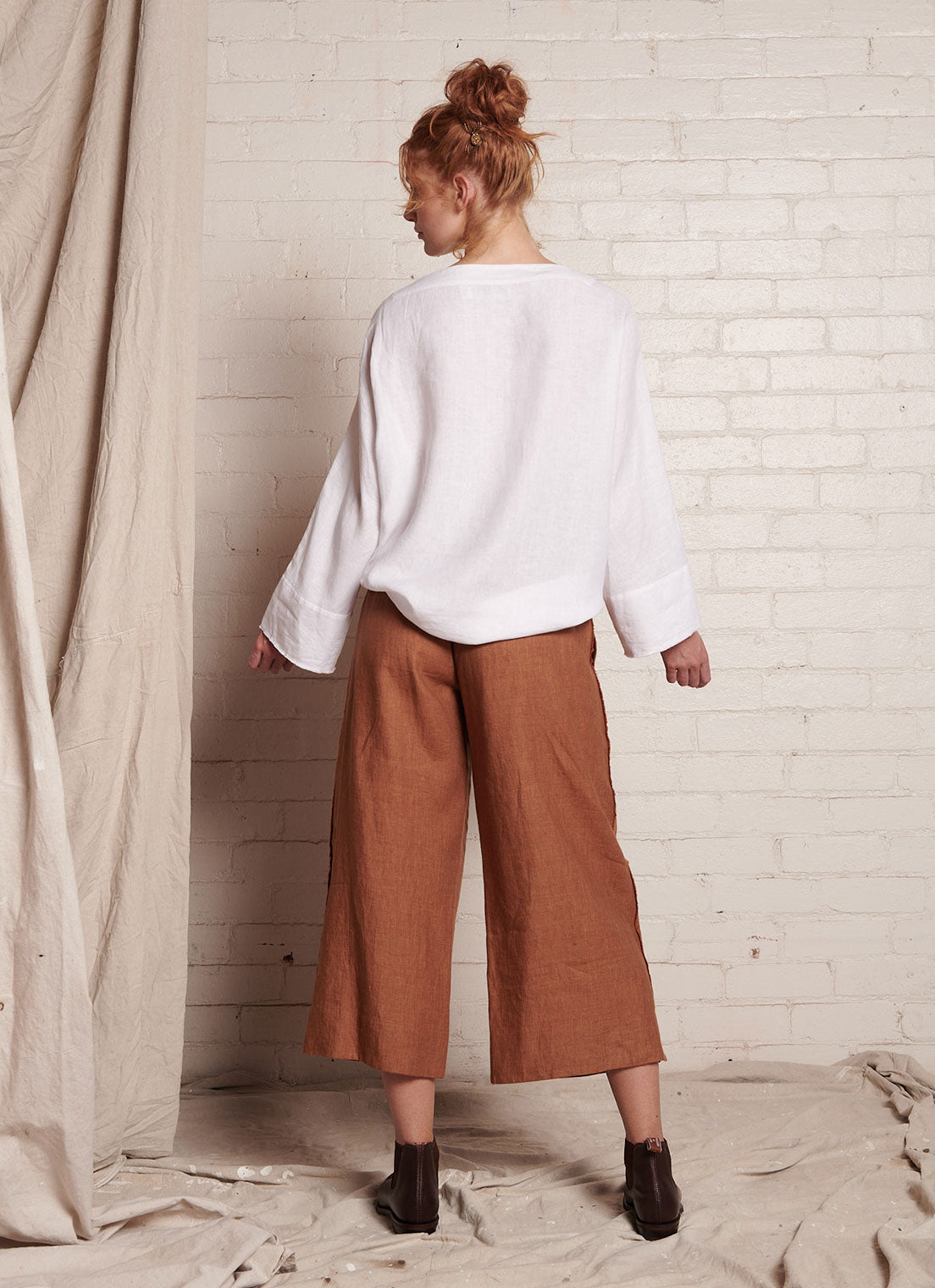 A bronze, loose fitting crop pants with elasticated back waistband, hand frayed detailing and tie belt of the same fabric