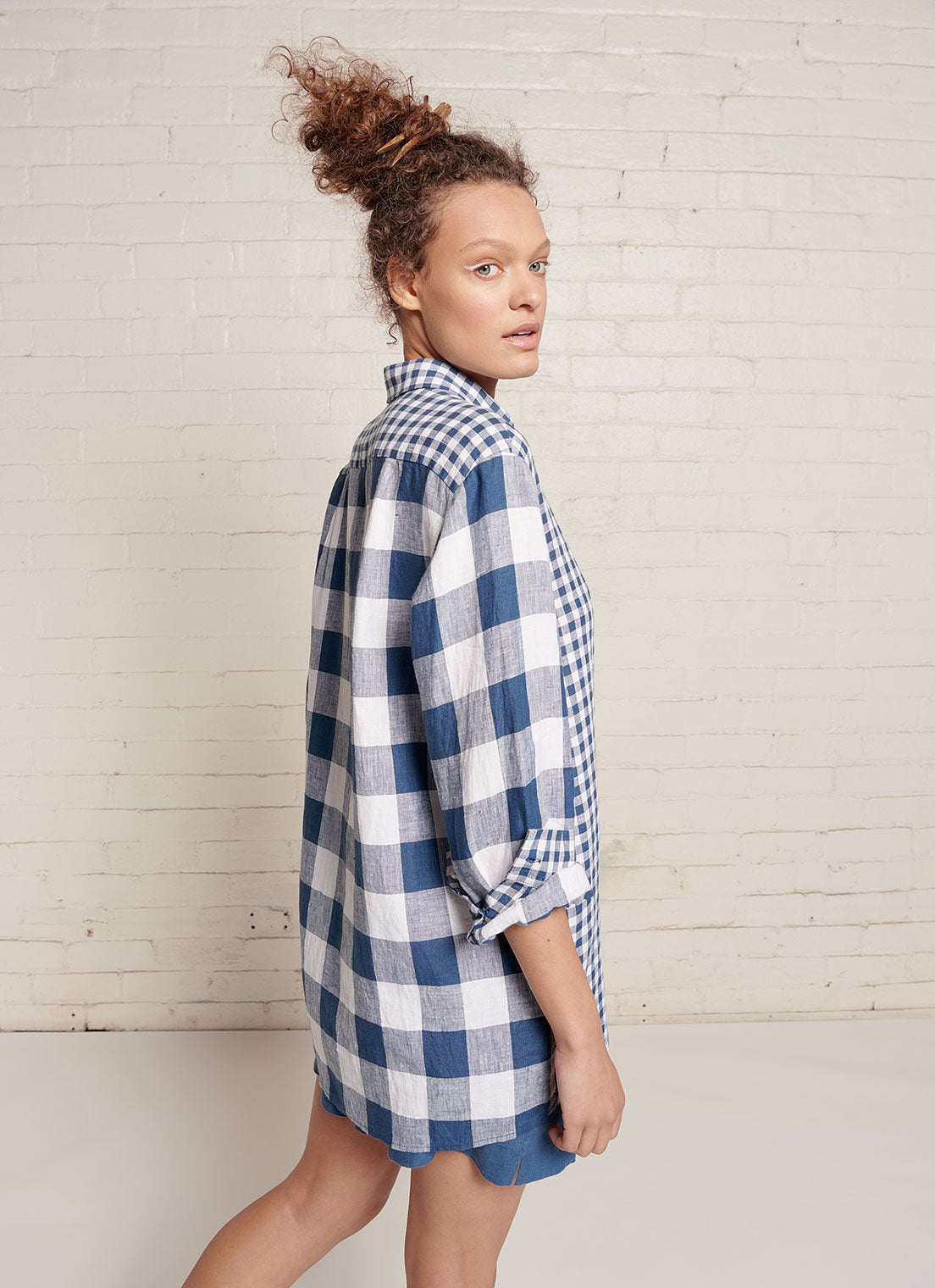 An indigo and white gingham, relaxed fit, unisex shirt with collar, sleeve cuff and centre front button fastening made from mixed gingham yarn dye washed linen