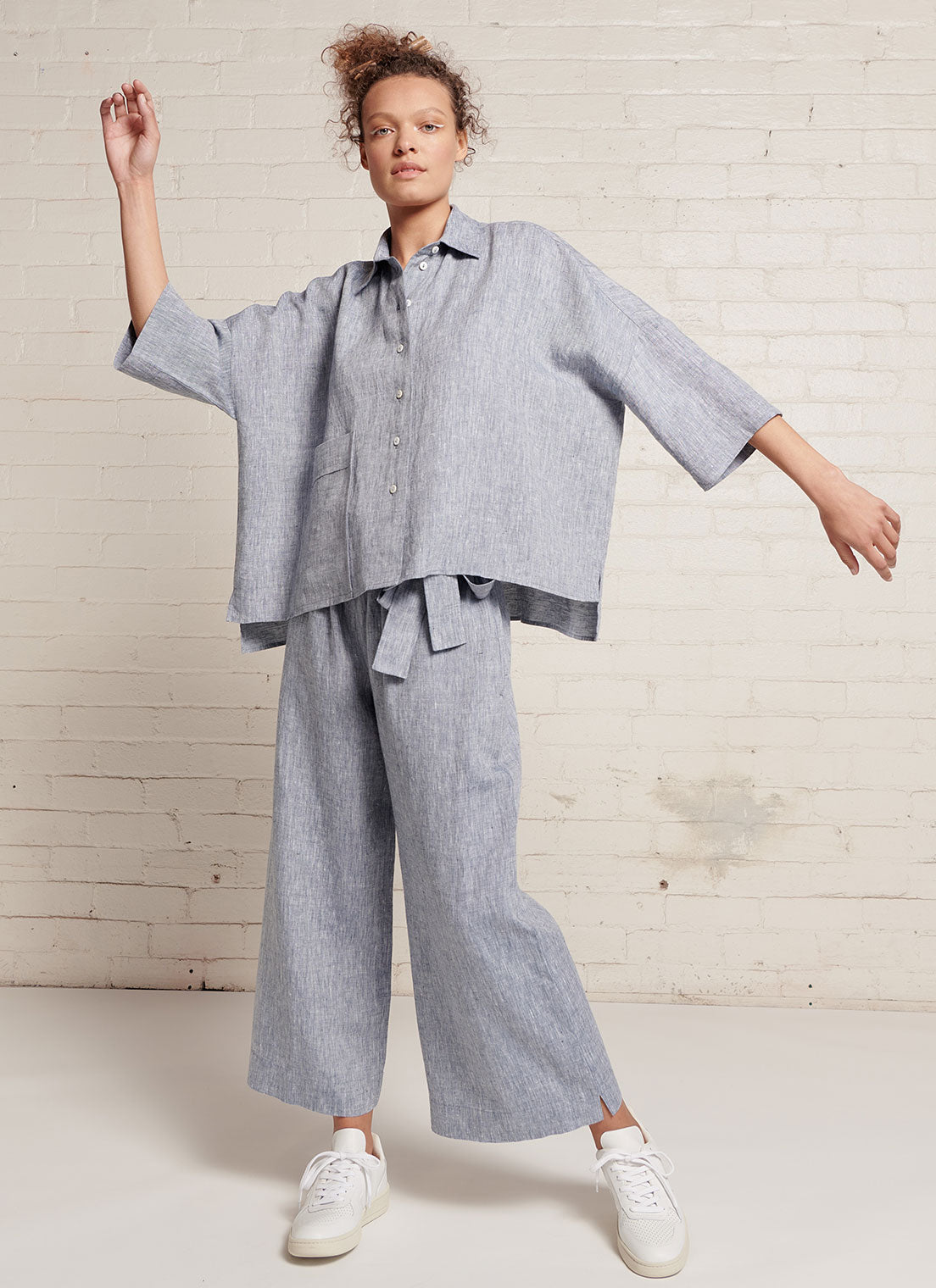 A denim, loose fitting crop pants with elasticated waistband and tie belt of the same fabric made from yarn dye washed linen