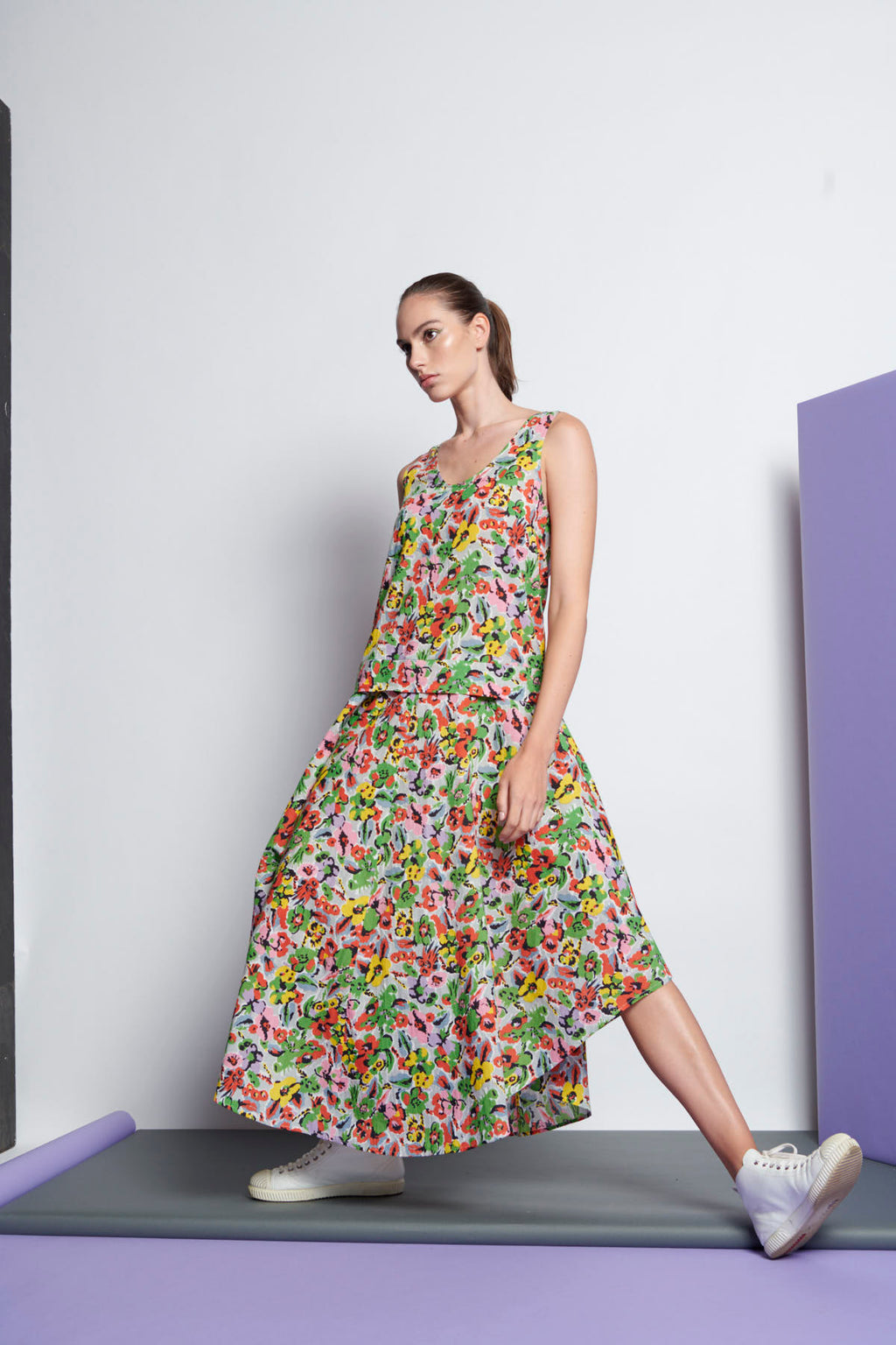 A floral, sleeveless dress that has a round neckline, dropped waist and cascading hem towards the middle