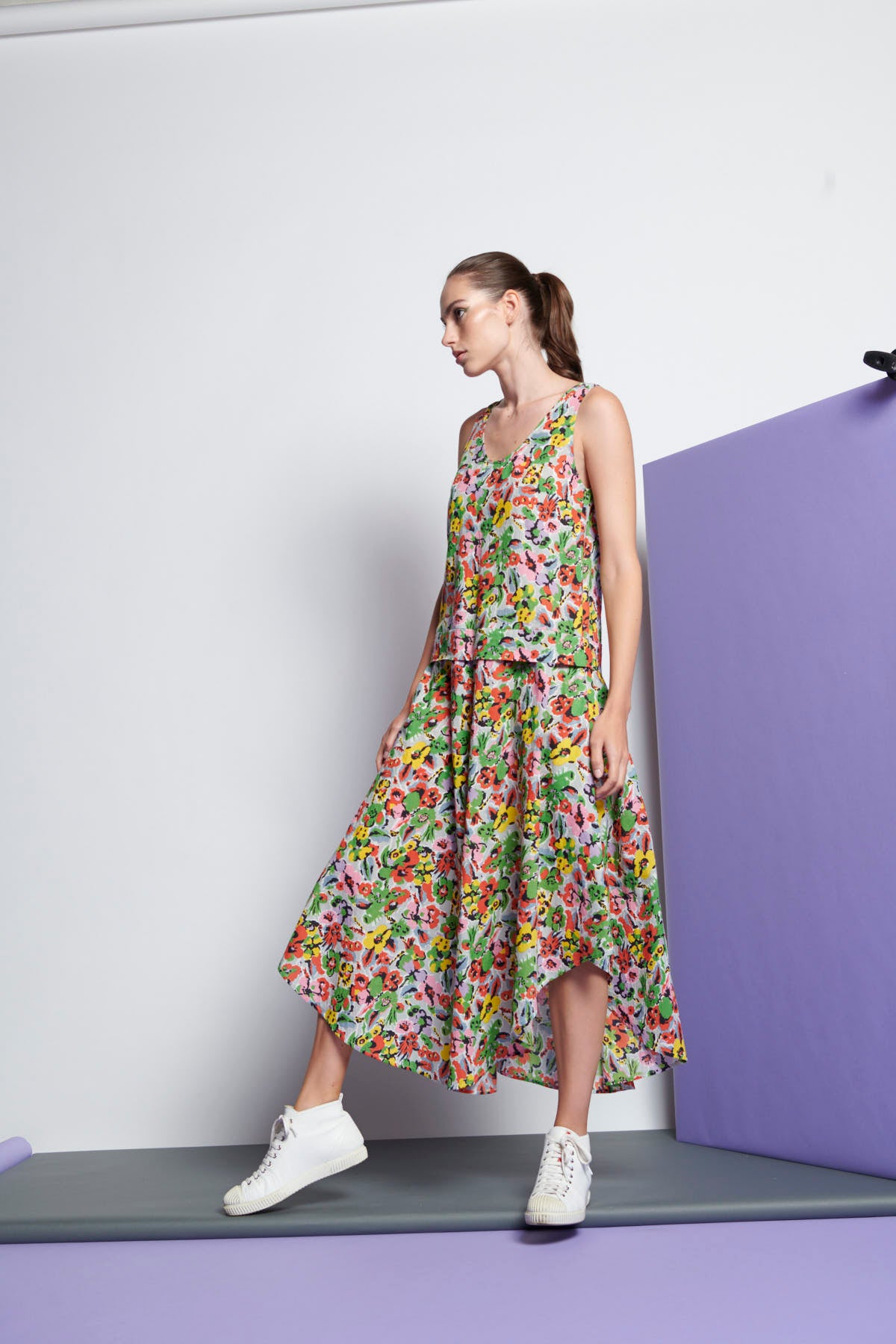 A floral, sleeveless dress that has a round neckline, dropped waist and cascading hem towards the middle