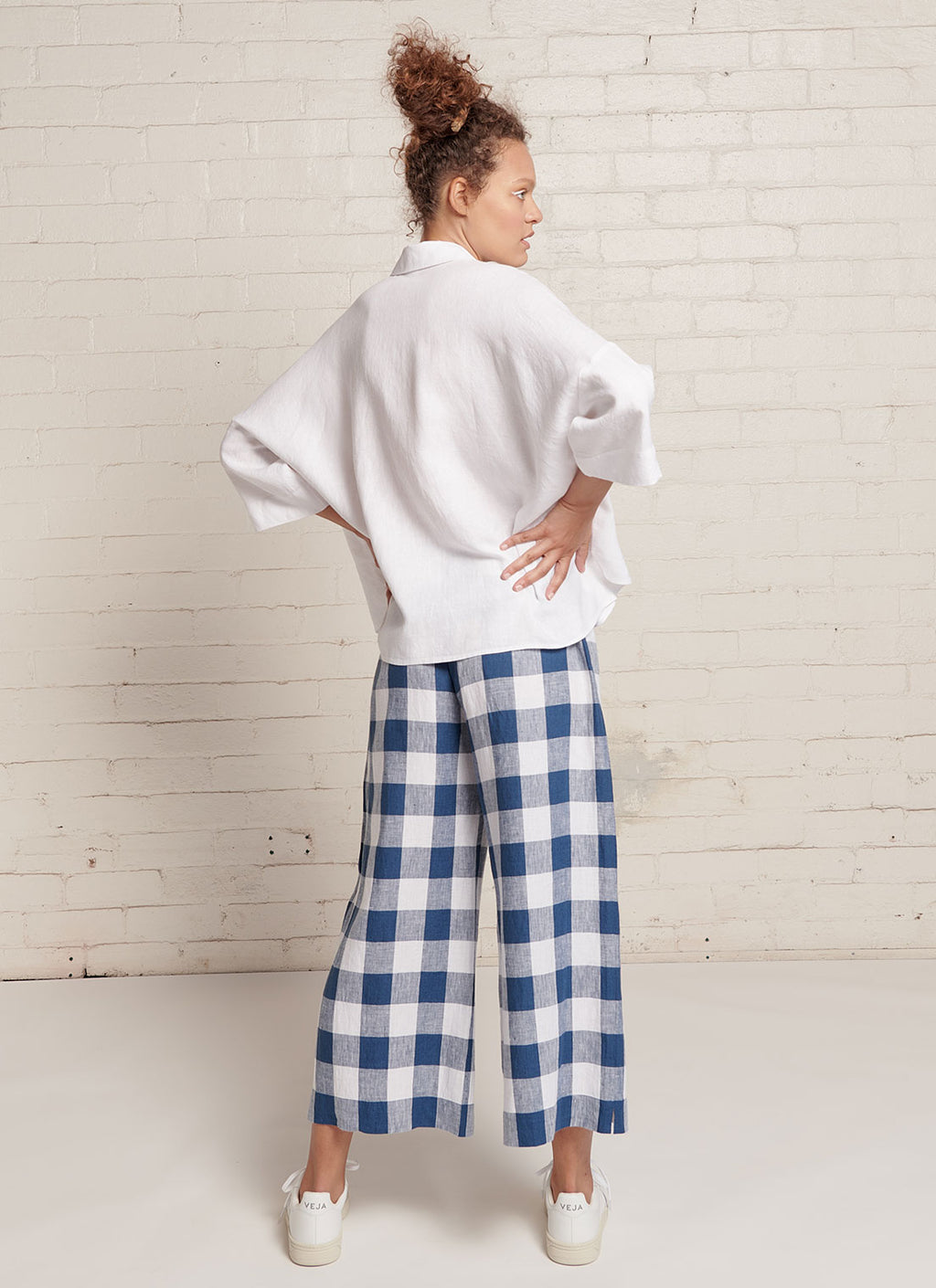 An indigo and white gingham, loose fitting crop pants with elasticated waistband and tie belt of the same fabric made from large gingham yarn dye washed linen