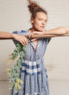An indigo and white gingham, patchwork, midi tiered dress with capped sleeves, pleated detail on the neckline and at the back, elastic waist and slits on the skirt made from mixed gingham yarn dye washed linen