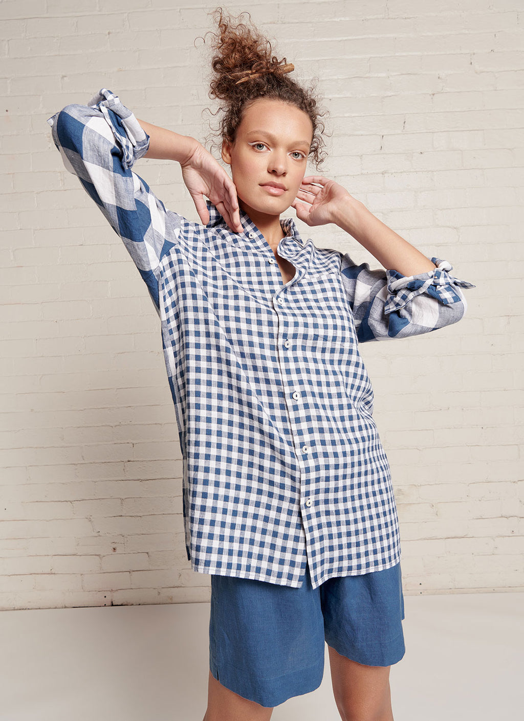 An indigo and white gingham, relaxed fit, unisex shirt with collar, sleeve cuff and centre front button fastening made from mixed gingham yarn dye washed linen