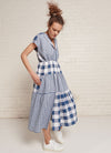 An indigo and white gingham, patchwork, midi tiered dress with capped sleeves, pleated detail on the neckline and at the back, elastic waist and slits on the skirt made from mixed gingham yarn dye washed linen