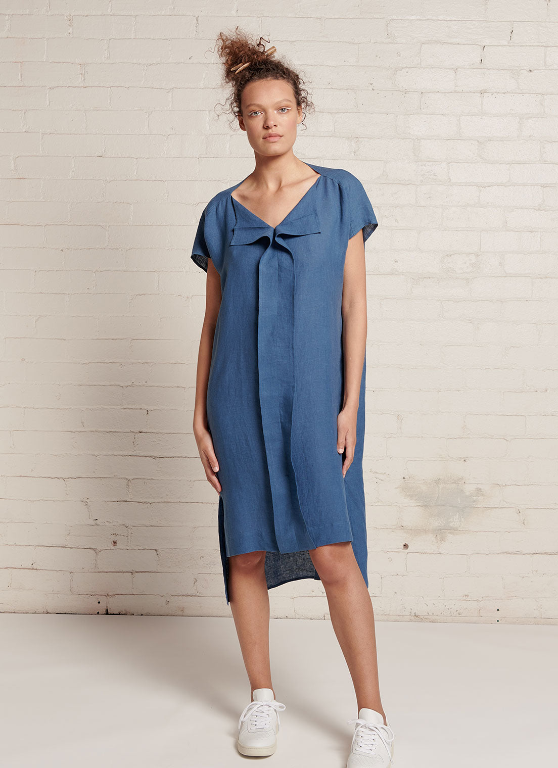 An indigo, knee-length linen dress with short sleeves, open neckline and centre front pleat detail made from yarn dye washed linen