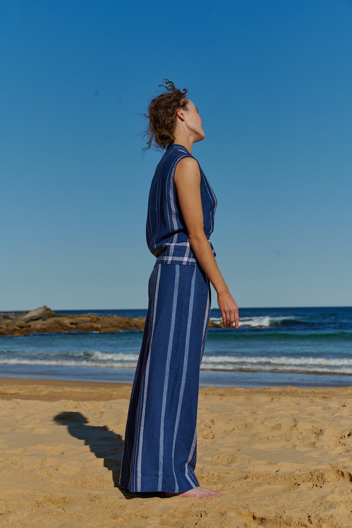 An indigo plaid, sleeveless, wrap linen top with V neckline and front tie belt 