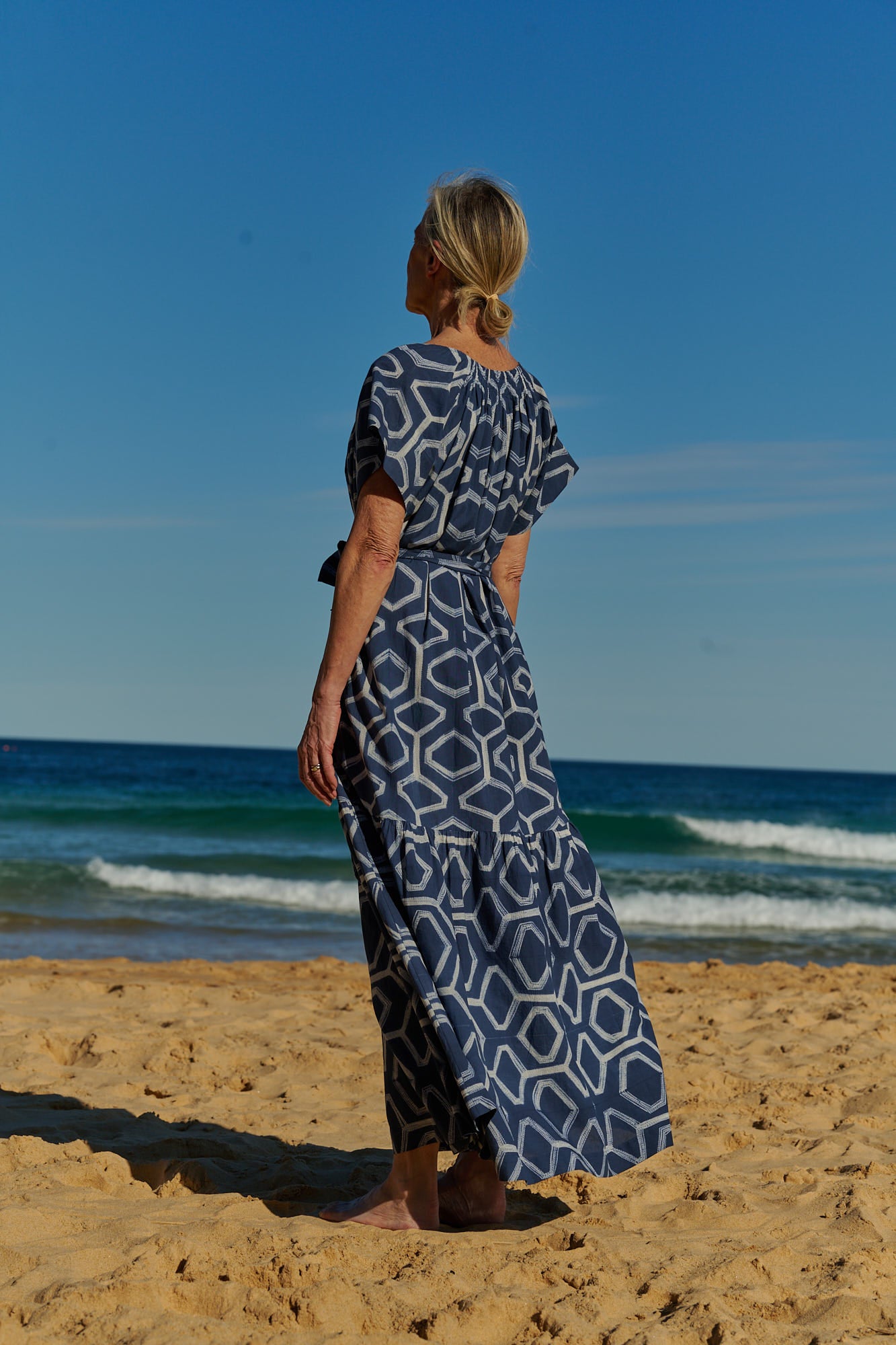A flowy, indigo, hand-dyed shibori cotton maxi dress with short sleeves and tie belt 