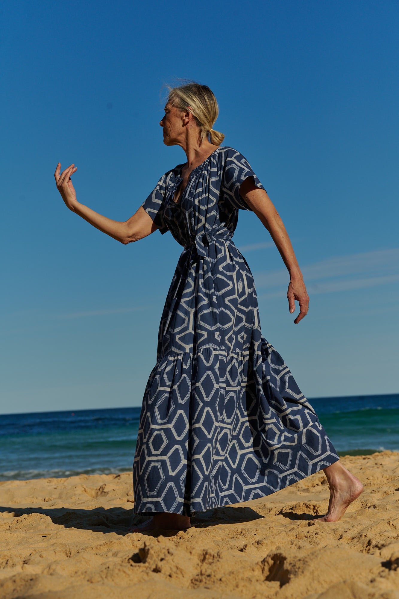 A flowy, indigo, hand-dyed shibori cotton maxi dress with short sleeves and tie belt 