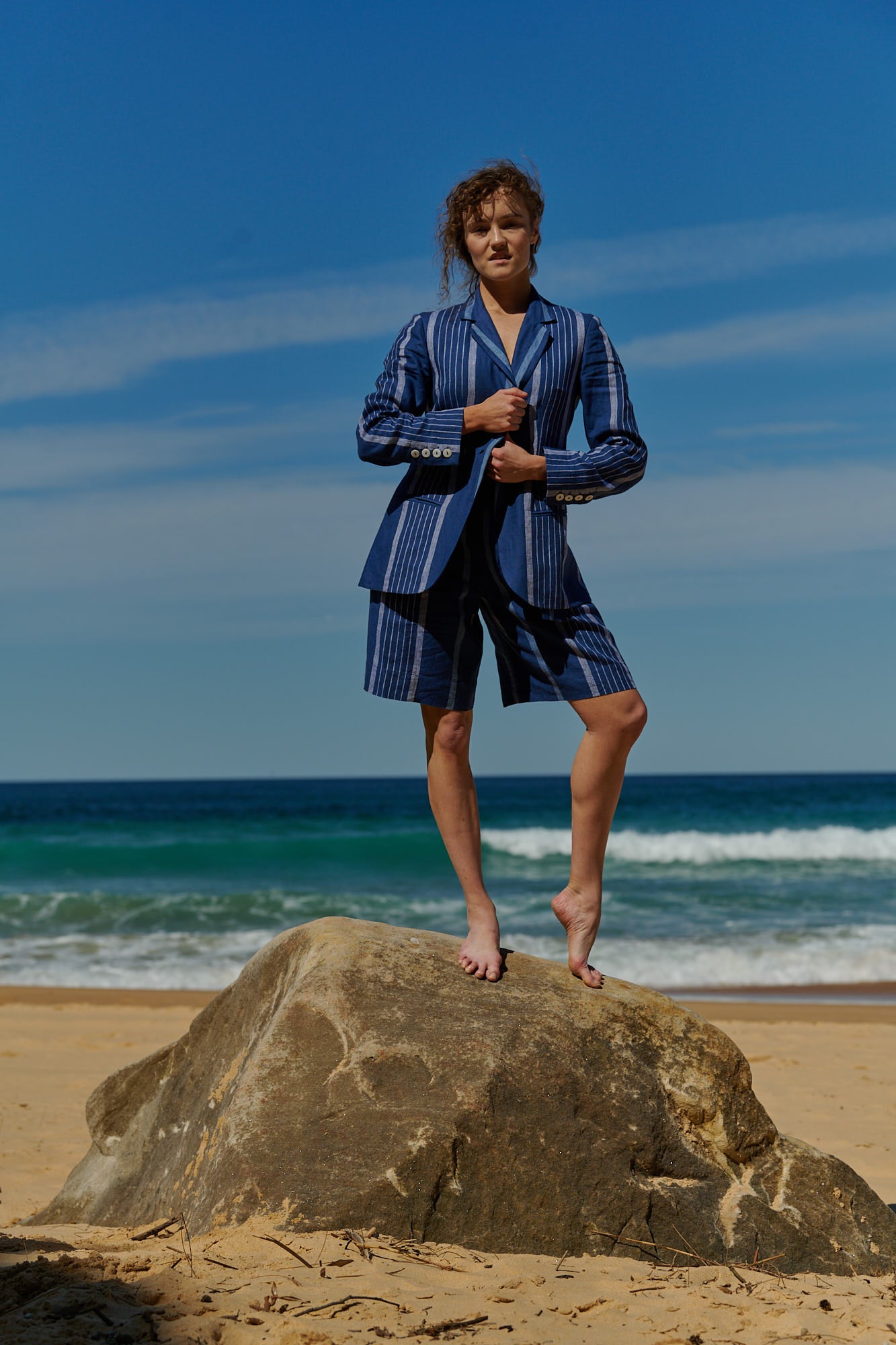 An indigo stripe linen blazer with single button, notched lapel, and double welt pockets 