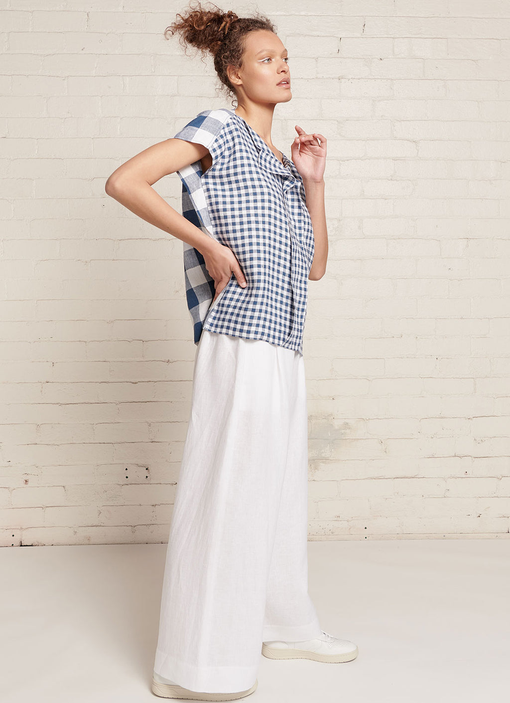An indigo and white gingham, square cut linen top with short sleeves, open V neckline and centre front pleat detail made from mixed gingham yarn dye washed linen