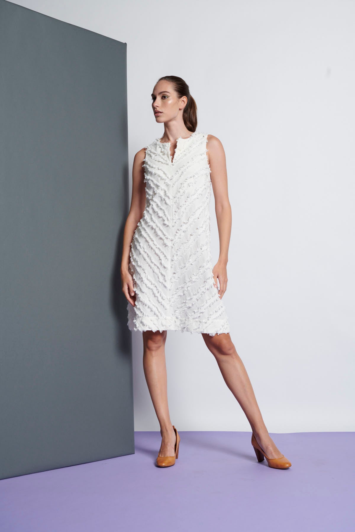 A white A-line cotton sleeveless dress that has a stripe fringe detail