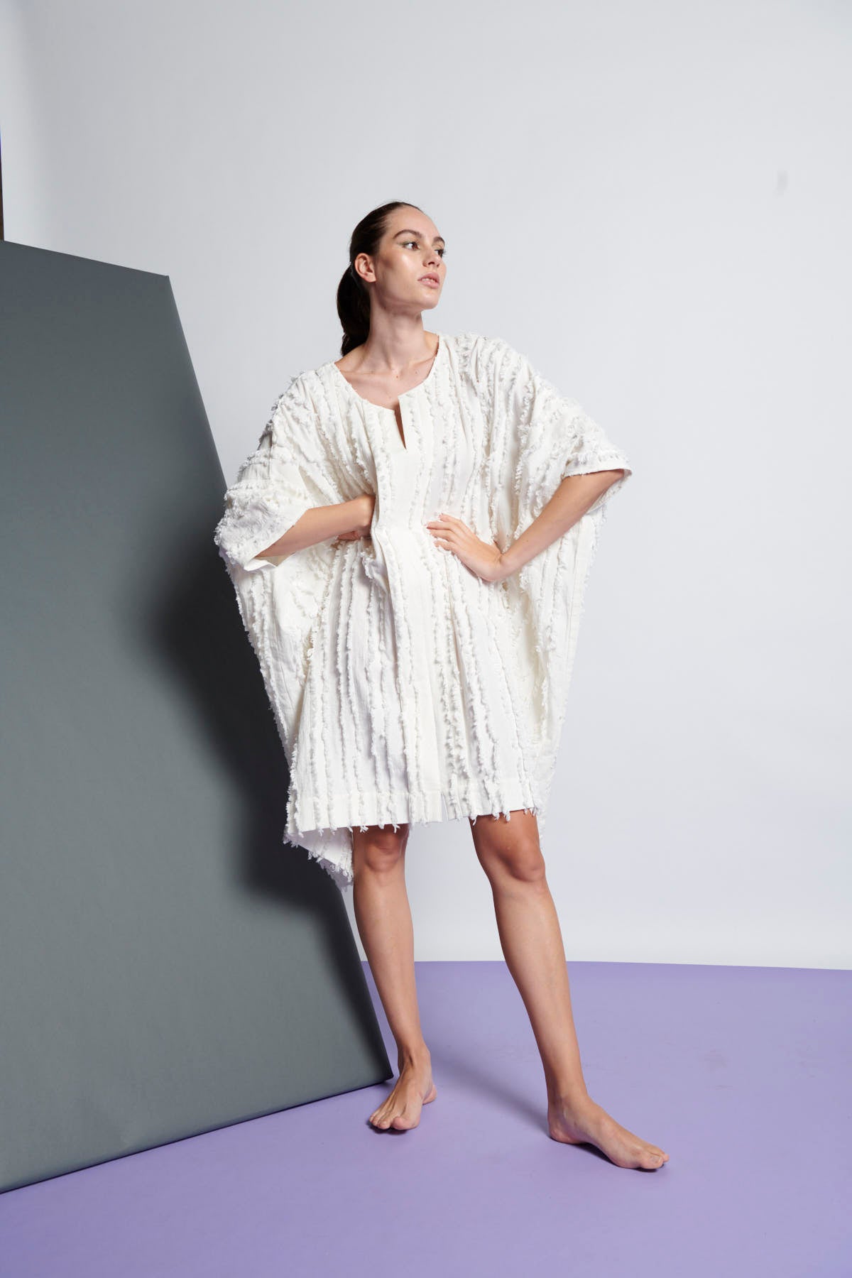 A white easy fit, square cut, knee-length dress made from cotton and linen with round neckline, short sleeves, and striped fringe fabric 