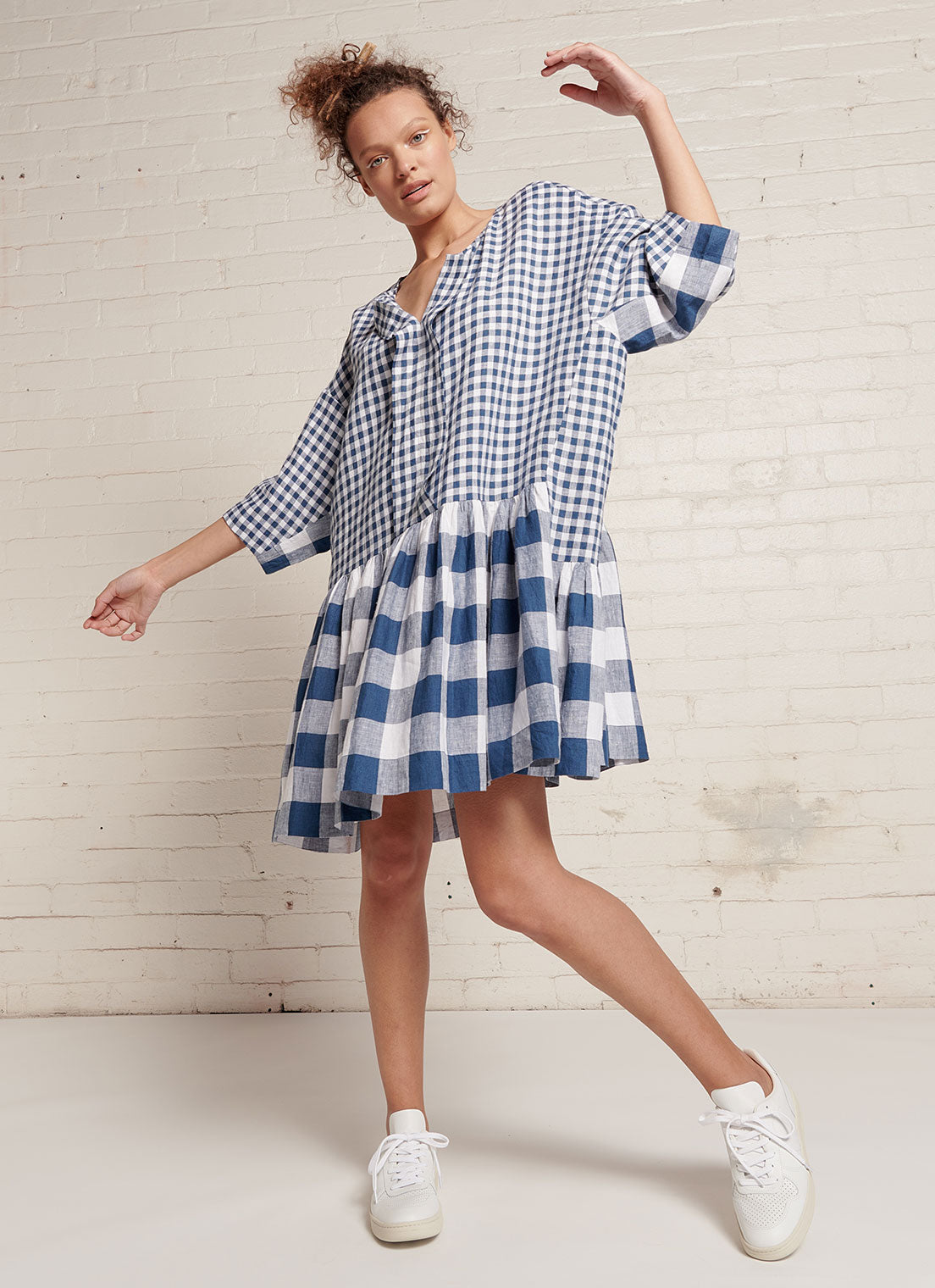An indigo and white gingham, easy fit, knee-length, square-cut dress with open neckline, 3/4 sleeves, and gathered detailing made from mixed gingham yarn dye washed linen