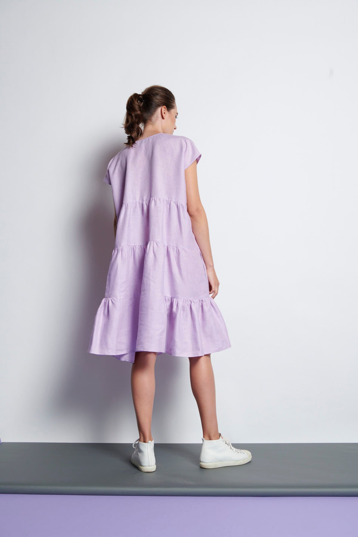 A lilac V-neckline, knee-length tiered dress with short sleeves made from pure linen