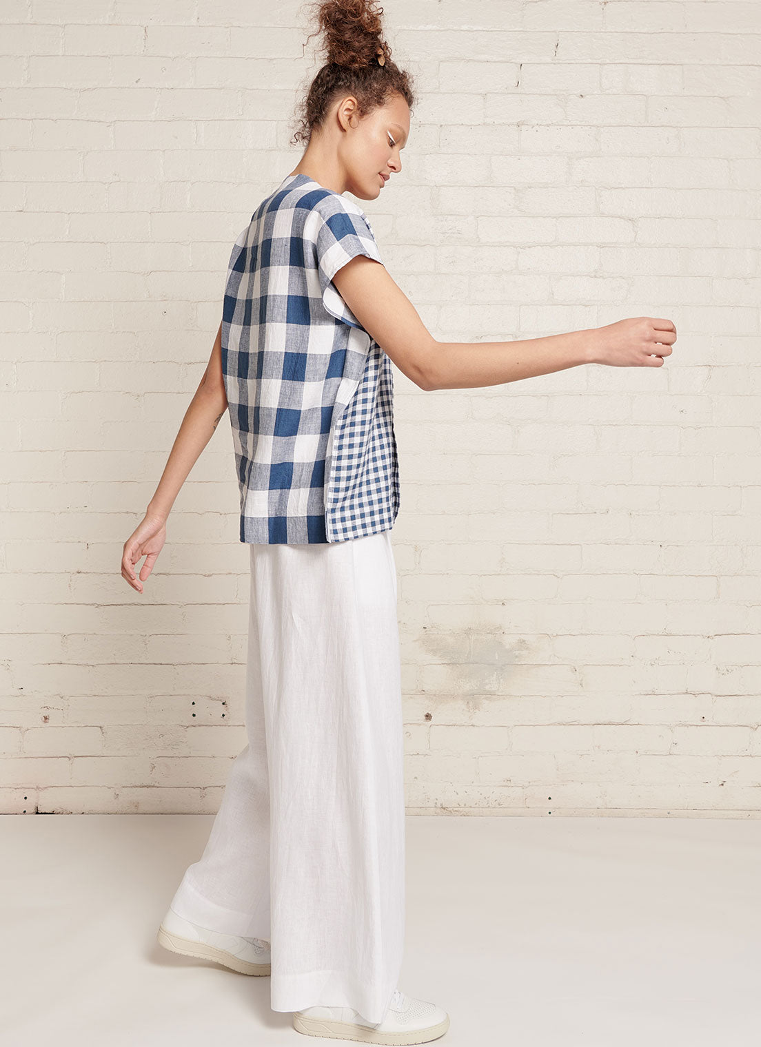 An indigo and white gingham, square cut linen top with short sleeves, open V neckline and centre front pleat detail made from mixed gingham yarn dye washed linen