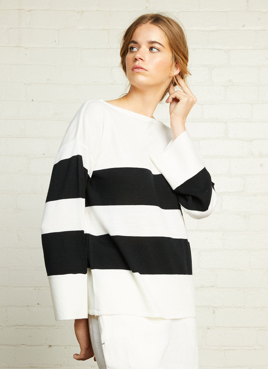 A black and white stripe boatneck sweater with relaxed fit and long sleeves made from merino wool