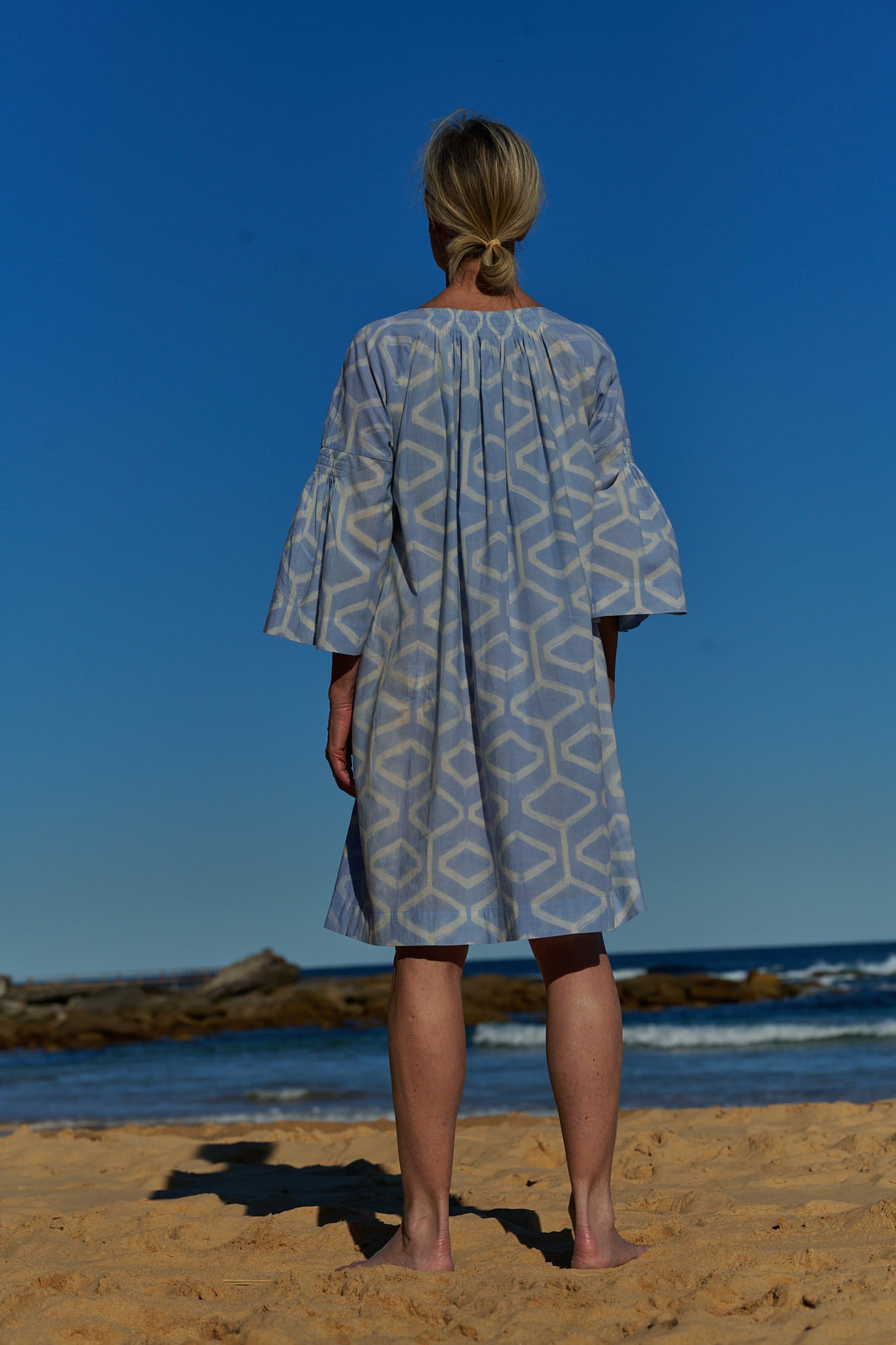 An easy fit, light blue shibori-dyed cotton dress with raglan bell sleeves and ruched detail at neckline