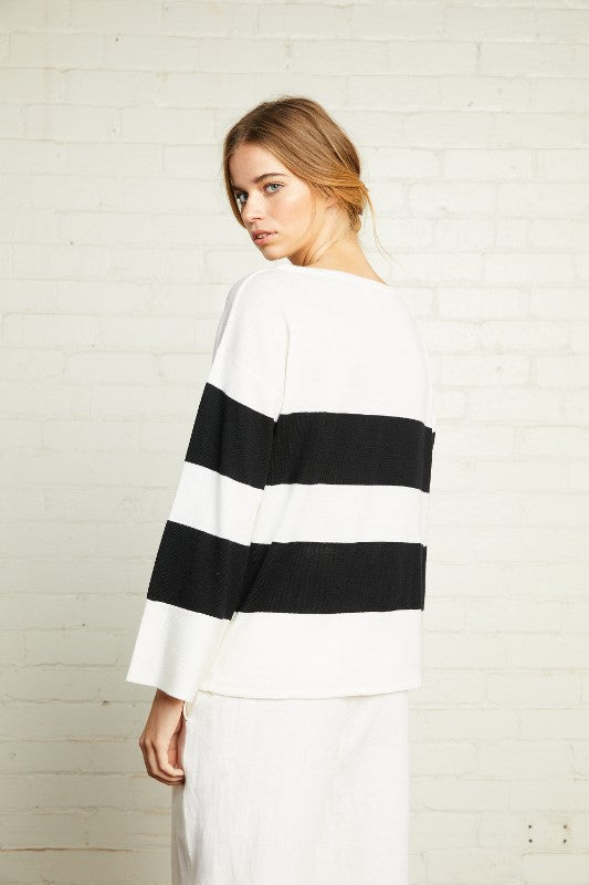 A black and white stripe boatneck knit top with relaxed fit and long sleeves made from merino wool