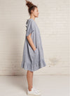 A denim, easy fit, knee-length, tiered dress with round neckline, short sleeves, tie closures at the back made from yarn dye washed linen