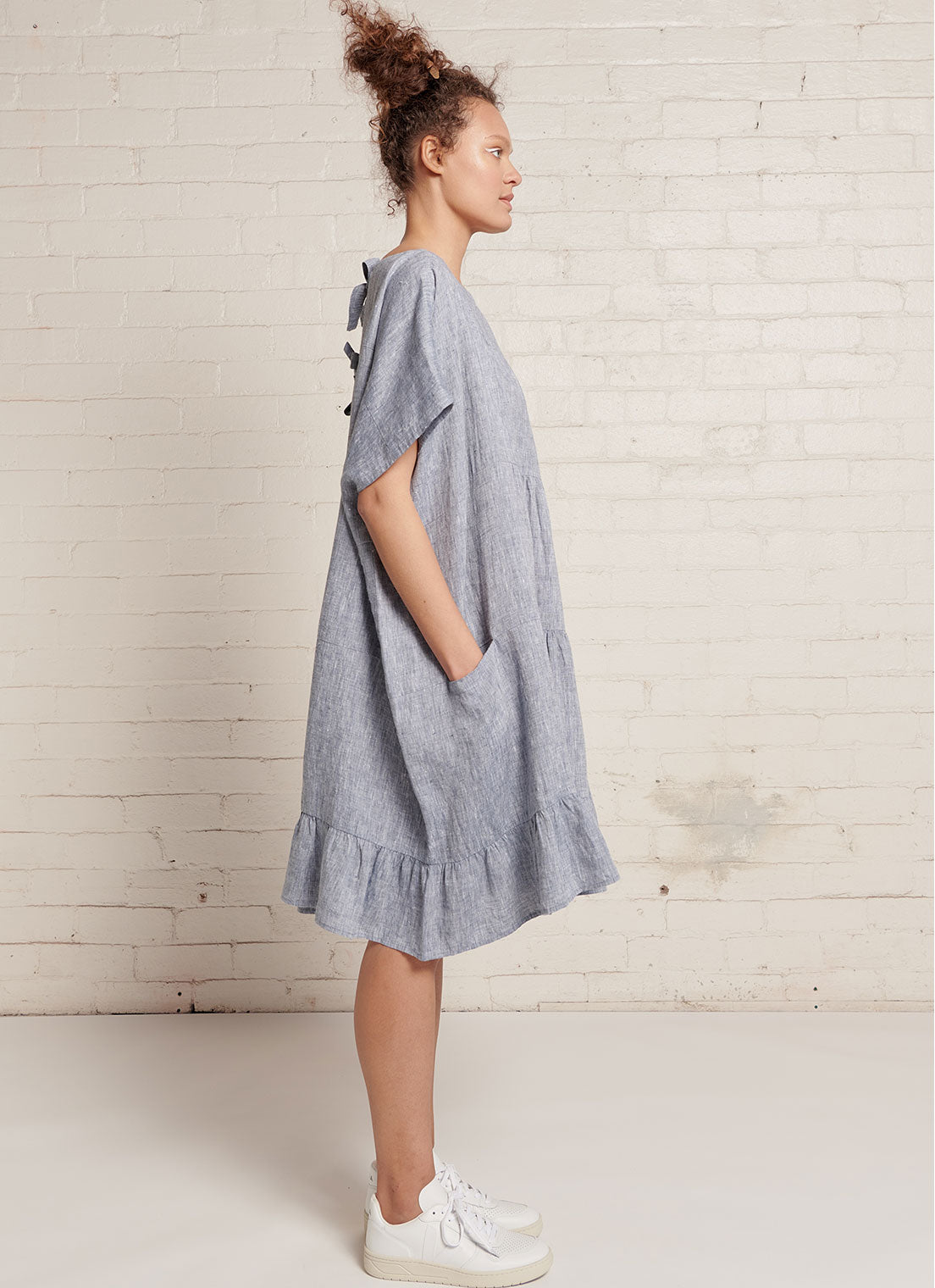 A denim, easy fit, knee-length, tiered dress with round neckline, short sleeves, tie closures at the back made from yarn dye washed linen
