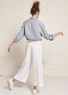 A white, loose fitting crop pants with elasticated waistband and tie belt of the same fabric made from yarn dye washed linen