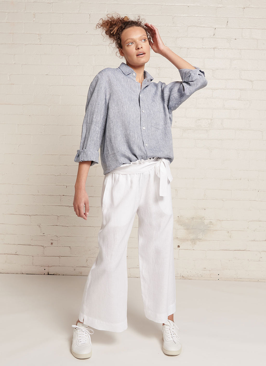 A white, loose fitting crop pants with elasticated waistband and tie belt of the same fabric made from yarn dye washed linen