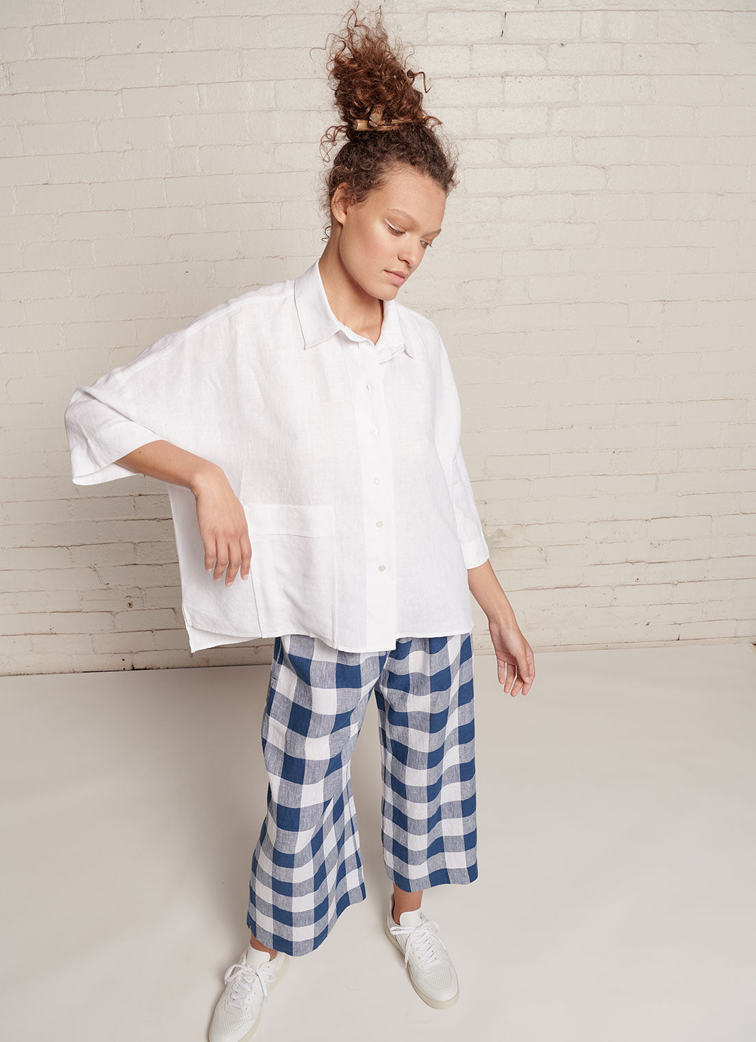 A white, relaxed fit, square cut, collared top with short sleeves, centre front button fastening and right front patch pocket made from yarn dye washed linen