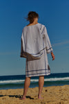 A white plaid linen, wrap around, knee-length skirt with waist ties and one side pocket