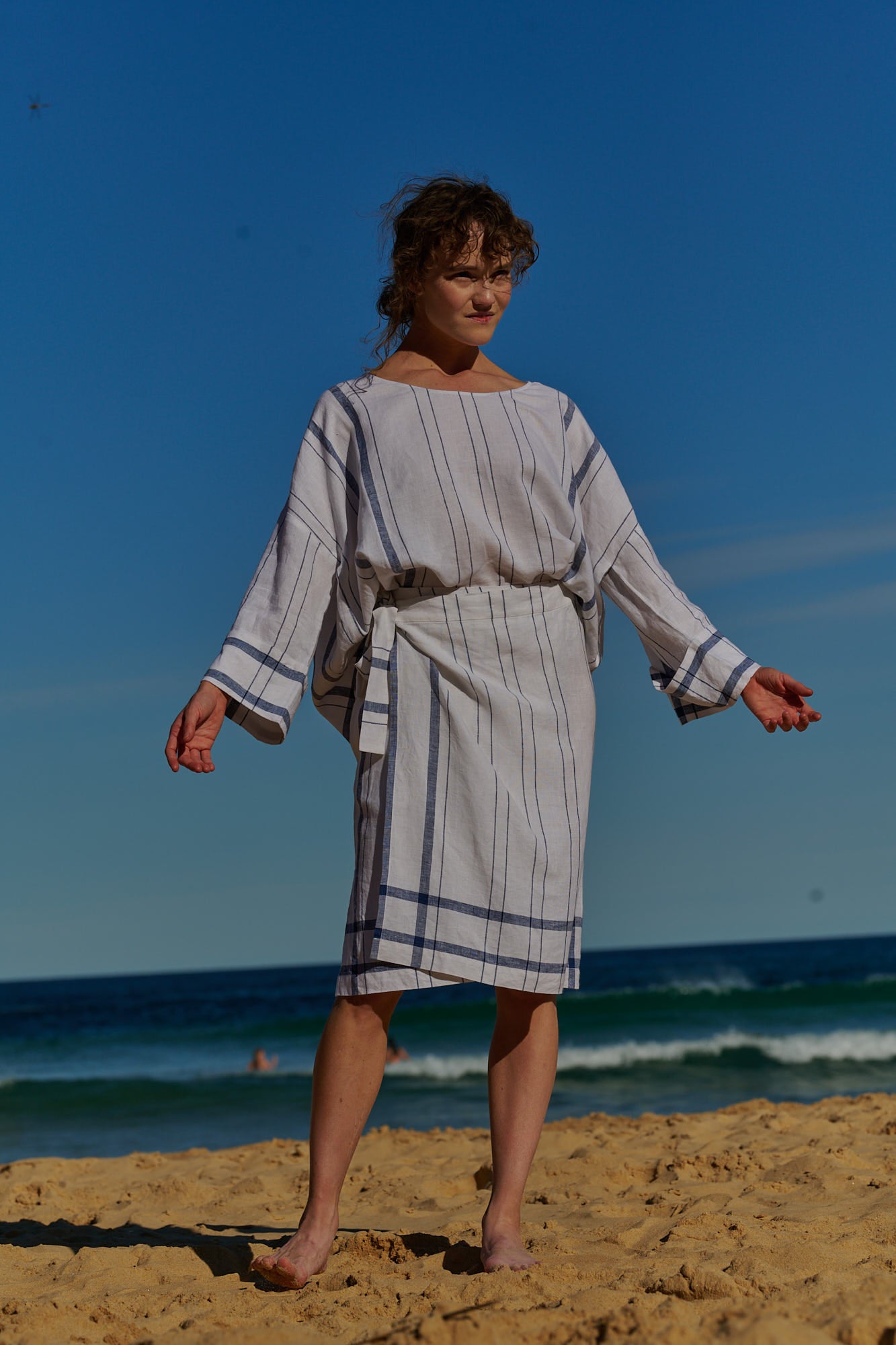 A white plaid linen, wrap around, knee-length skirt with waist ties and one side pocket