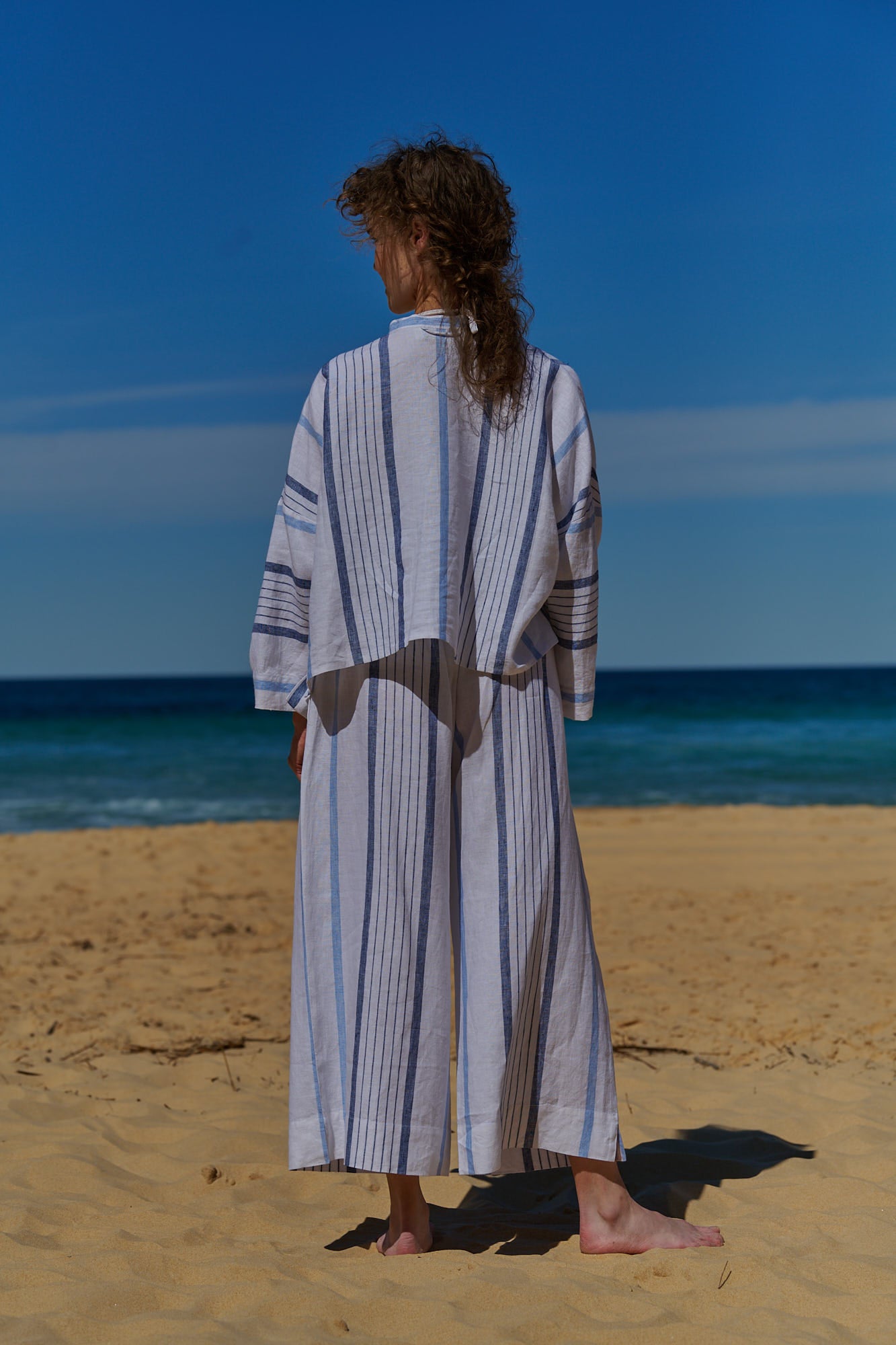 A white stripe linen, cropped pants with a wide, elasticised waistband, belt of the same fabric and pockets