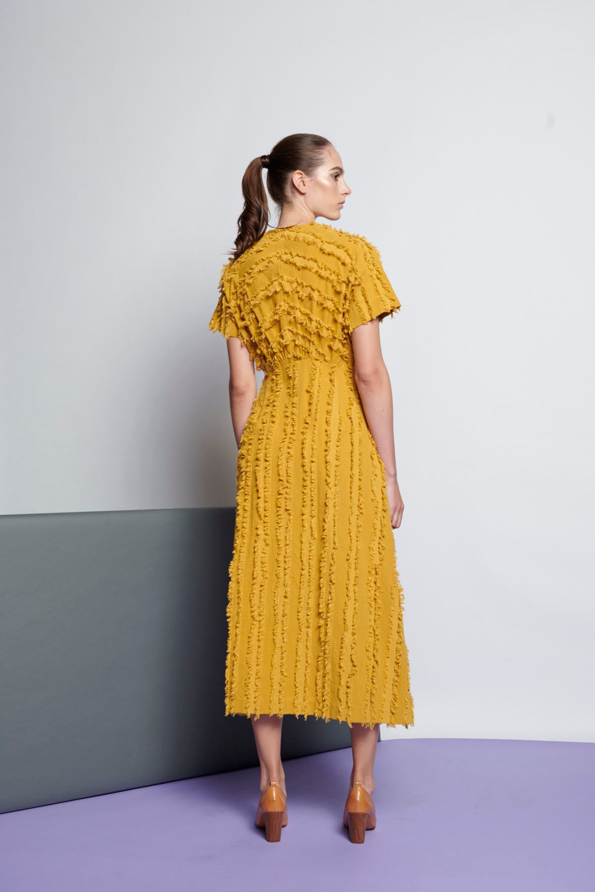 A yellow cotton empire-cut and midi-length dress with V-neckline, short sleeves, and stripe fringe texture.