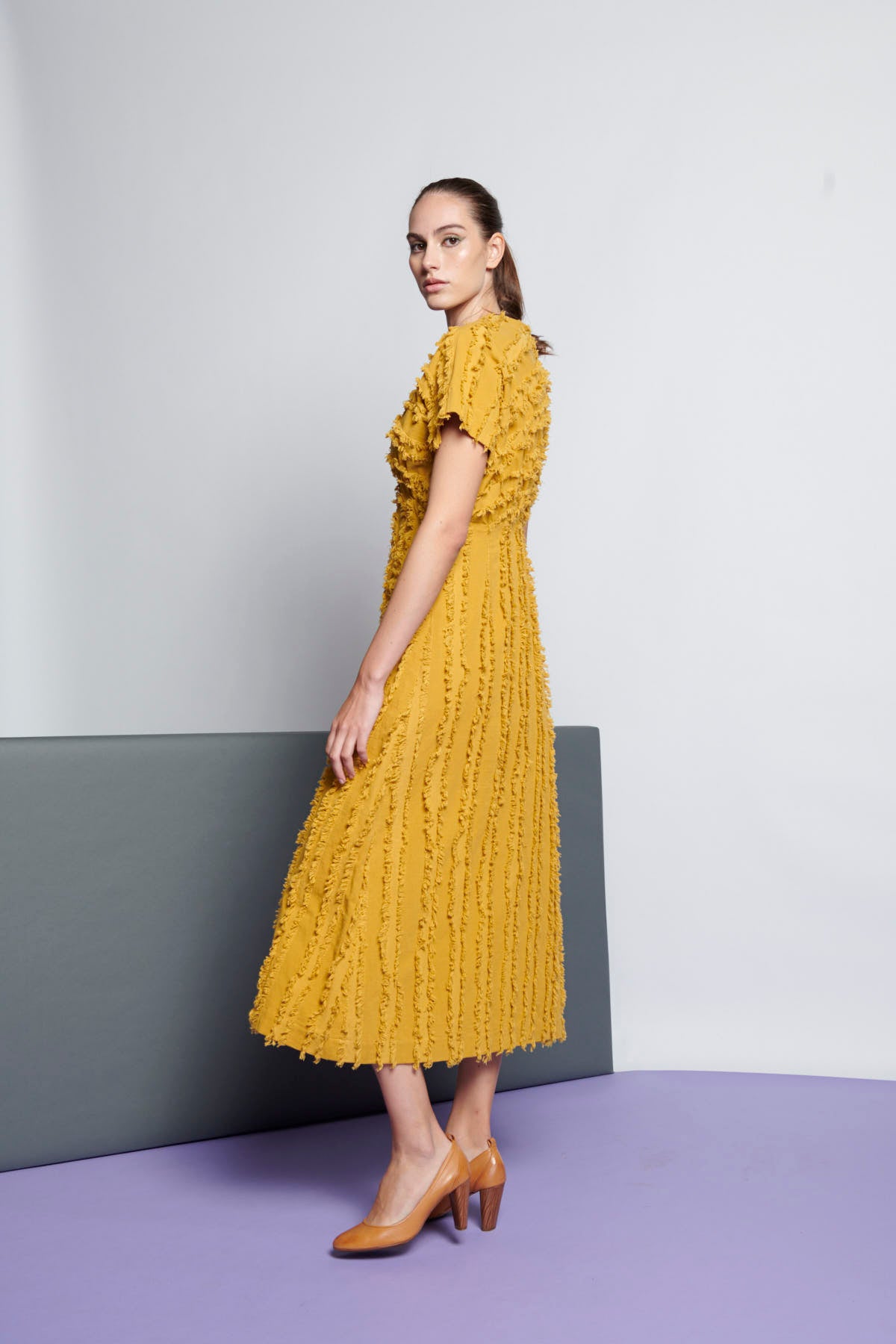 A yellow cotton empire-cut and midi-length dress with V-neckline, short sleeves, and stripe fringe texture.